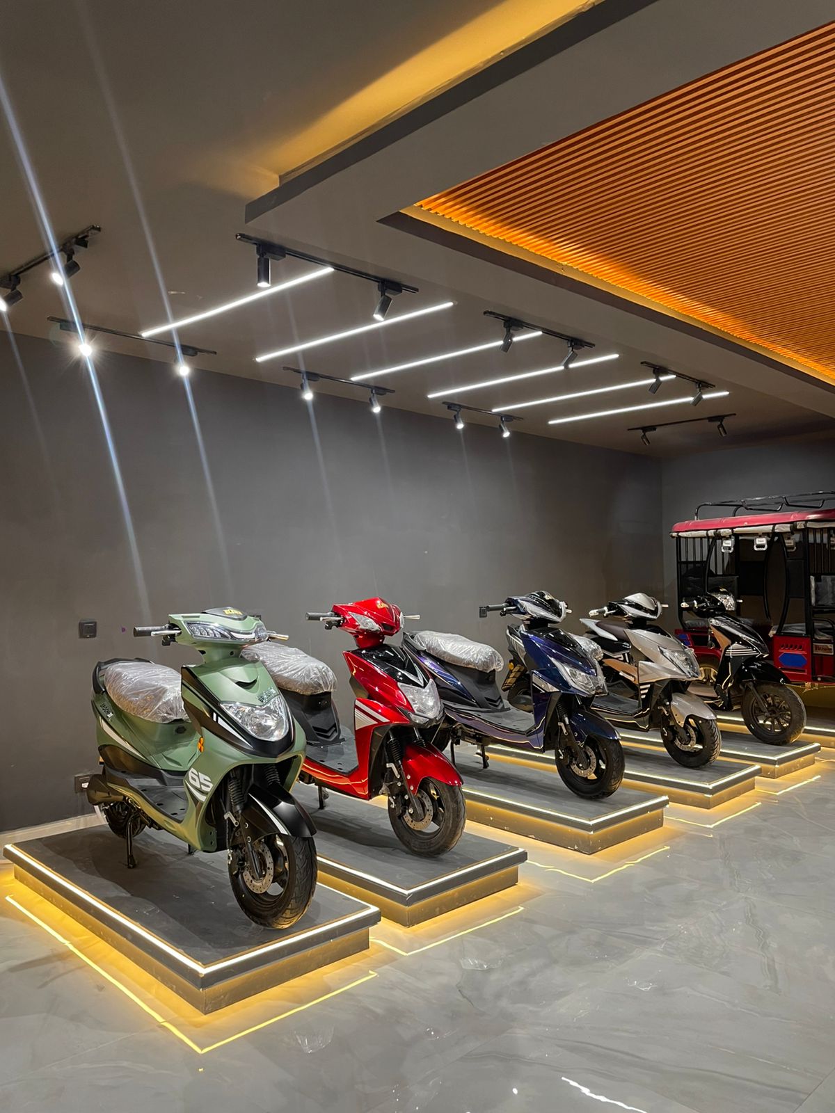 Ad Value Global electric scooter showroom with lit display podiums and warm strip lighting